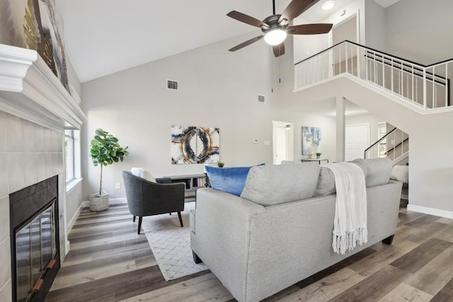 living area featuring visible vents, ceiling fan, stairs, a fireplace, and wood finished floors