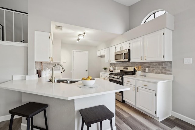 kitchen featuring a breakfast bar area, a peninsula, a sink, stainless steel appliances, and tasteful backsplash