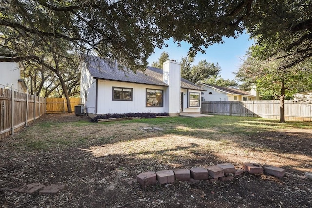 rear view of property featuring a shingled roof, cooling unit, a fenced backyard, and a chimney