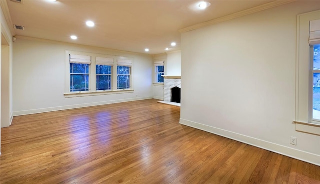 unfurnished living room with visible vents, crown molding, baseboards, and wood finished floors