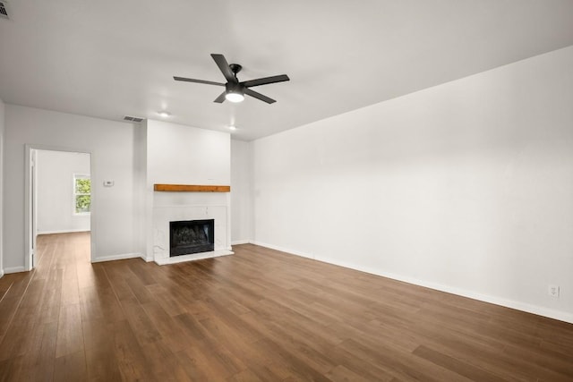 unfurnished living room featuring visible vents, a fireplace, dark wood-type flooring, and ceiling fan