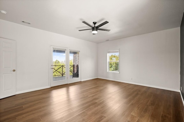 unfurnished room with wood finished floors, a ceiling fan, visible vents, and baseboards