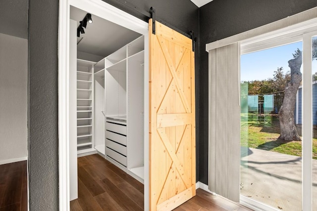 walk in closet with a barn door and wood finished floors