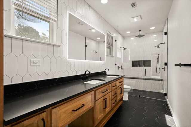 6607 Avenida Ann Dr, Lago Vista, TX 78645 - bathroom featuring a tile shower, toilet, double vanity, decorative backsplash, and tile patterned flooring