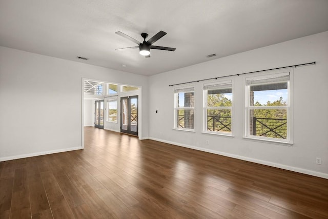 unfurnished living room featuring visible vents, baseboards, a ceiling fan, and dark wood-style flooring