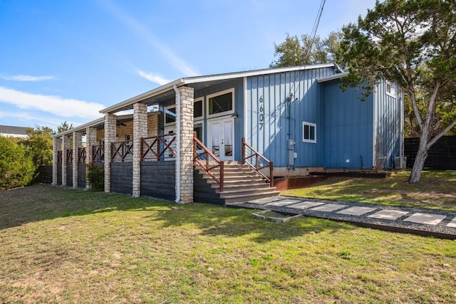 rear view of house with a yard, board and batten siding, and french doors