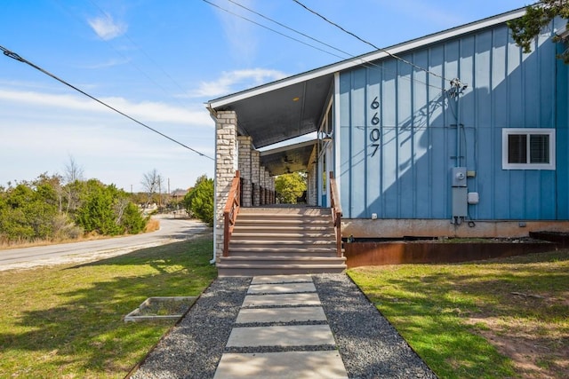 view of exterior entry with a lawn and board and batten siding