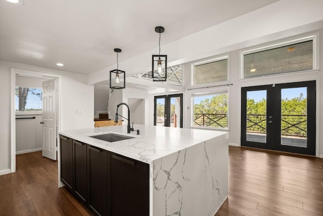 kitchen featuring light stone countertops, dark wood finished floors, a sink, hanging light fixtures, and french doors