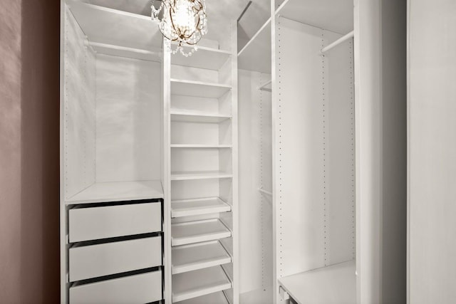 walk in closet with a notable chandelier