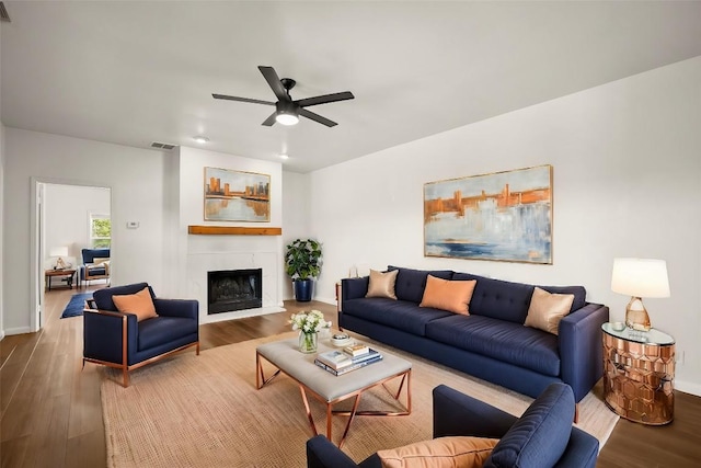 living area featuring a fireplace, wood finished floors, visible vents, and ceiling fan