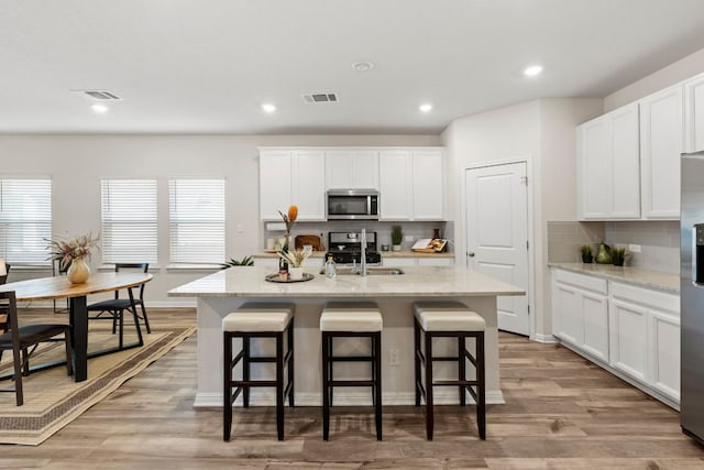 kitchen featuring a sink, visible vents, a kitchen breakfast bar, and appliances with stainless steel finishes