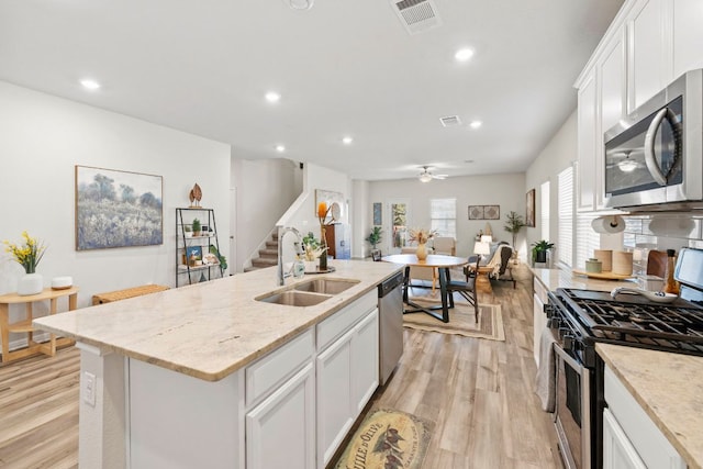 kitchen featuring visible vents, a sink, white cabinetry, light wood-style floors, and appliances with stainless steel finishes