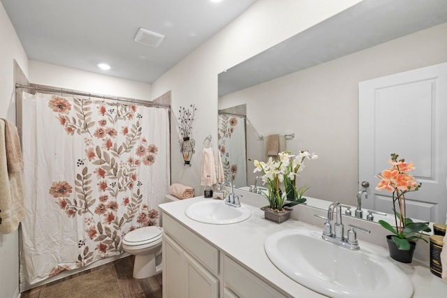 bathroom featuring double vanity, visible vents, toilet, and a sink