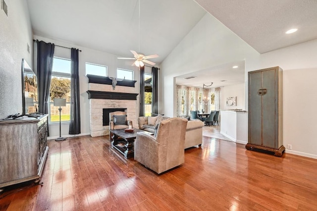 living room with visible vents, hardwood / wood-style floors, a fireplace, baseboards, and ceiling fan