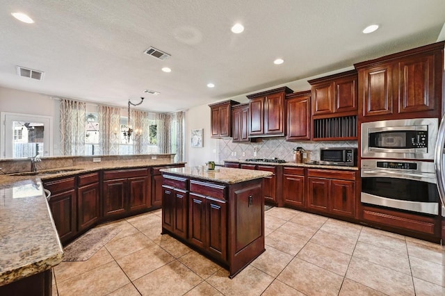 kitchen with visible vents, backsplash, stainless steel appliances, and a sink