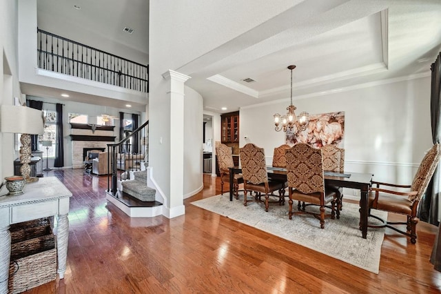 dining space featuring visible vents, stairs, a tray ceiling, and hardwood / wood-style floors