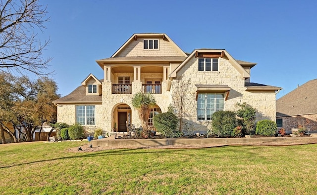 view of front of house featuring stone siding, a front lawn, and a balcony