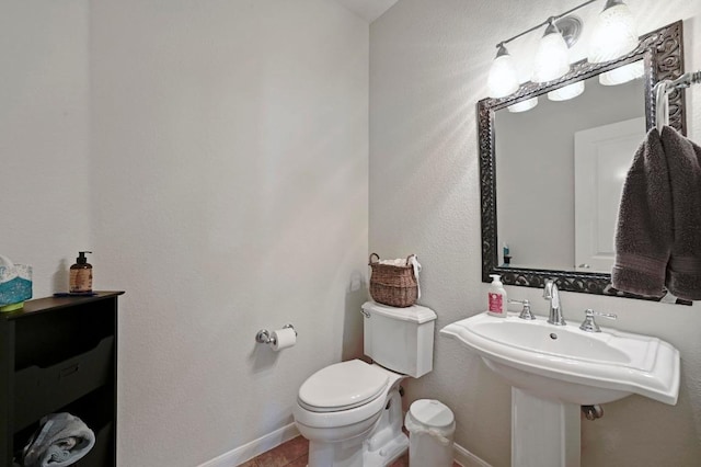 half bath with a sink, baseboards, toilet, and tile patterned flooring