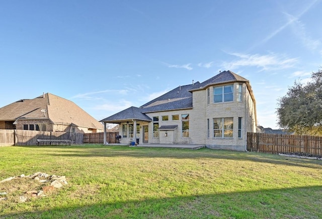 back of house featuring a gazebo, a yard, fence, and stone siding