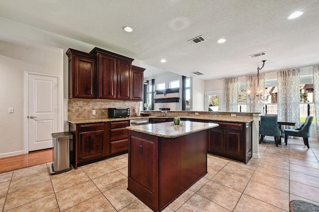 kitchen with a chandelier, visible vents, backsplash, and a center island