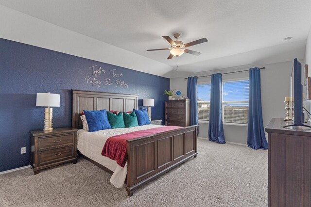 bedroom featuring baseboards, ceiling fan, vaulted ceiling, light carpet, and a textured wall