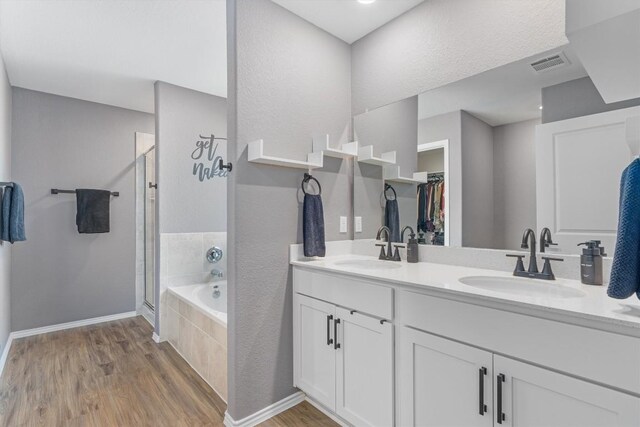 full bathroom with visible vents, a stall shower, a sink, wood finished floors, and a bath