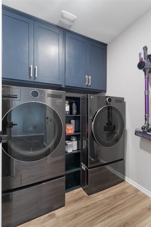 washroom with visible vents, cabinet space, light wood-style floors, and washer and clothes dryer