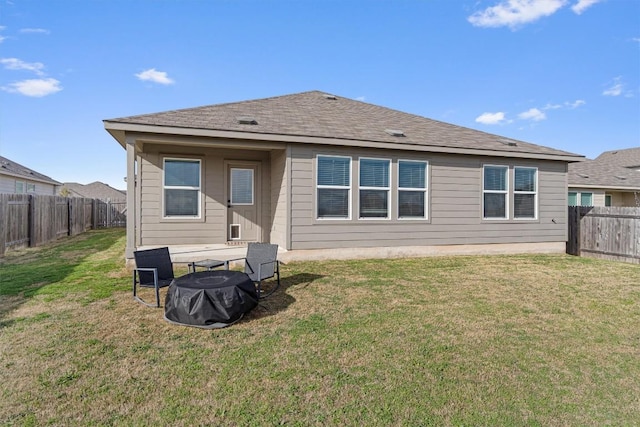 back of house featuring a lawn, a shingled roof, and a fenced backyard