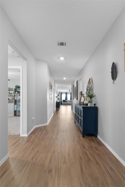 corridor with visible vents, baseboards, and wood finished floors