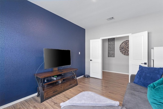 living room with wood finished floors, visible vents, and baseboards