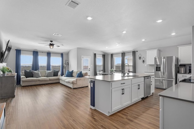 kitchen with visible vents, white cabinetry, stainless steel appliances, and a sink