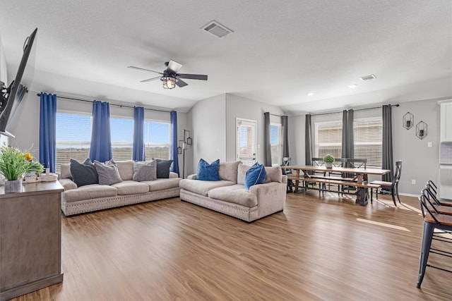 living area featuring visible vents, lofted ceiling, ceiling fan, and wood finished floors