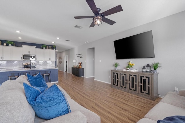 living area with visible vents, ceiling fan, baseboards, recessed lighting, and light wood-style floors