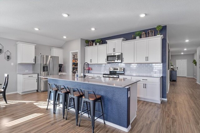 kitchen featuring a kitchen island with sink, light wood-type flooring, appliances with stainless steel finishes, and a sink