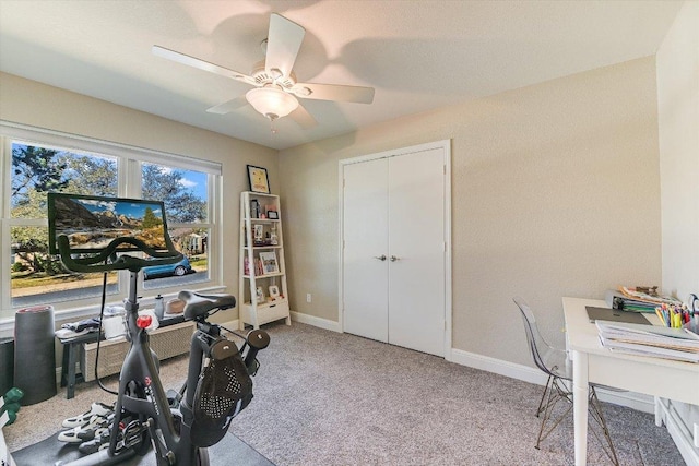 carpeted office featuring baseboards and a ceiling fan