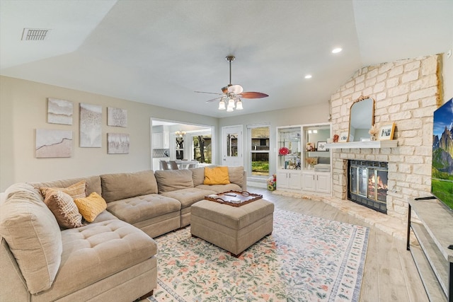 living area with visible vents, vaulted ceiling, a fireplace, wood finished floors, and a ceiling fan