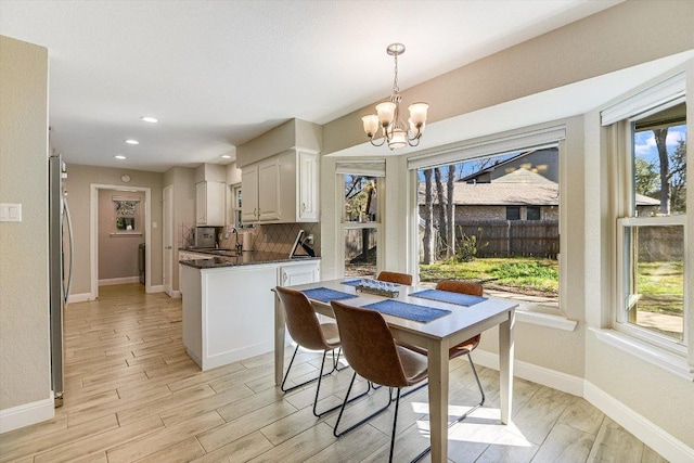 dining space featuring a wealth of natural light, baseboards, a chandelier, and light wood finished floors