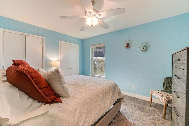 bedroom featuring carpet flooring, baseboards, multiple closets, and a ceiling fan