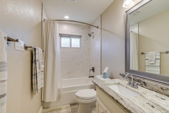 full bath with visible vents, toilet, shower / tub combo, a textured wall, and vanity