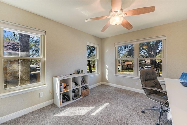 carpeted office space featuring baseboards and ceiling fan