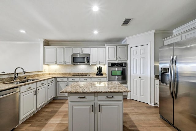 kitchen featuring visible vents, a sink, tasteful backsplash, wood finished floors, and stainless steel appliances