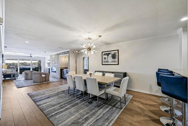 dining area with baseboards, a chandelier, ornamental molding, wood finished floors, and a textured ceiling