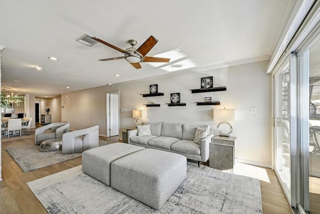 living area featuring visible vents, baseboards, recessed lighting, ceiling fan with notable chandelier, and wood finished floors