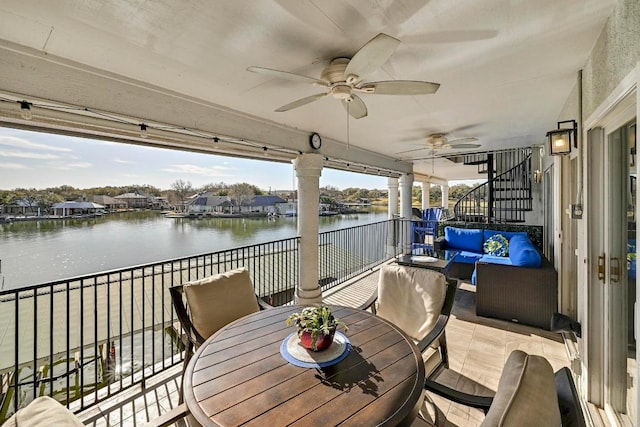 deck with stairs, a water view, outdoor dining space, and a ceiling fan