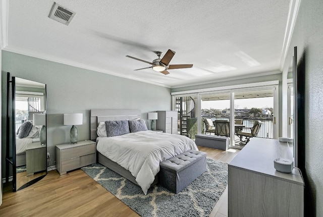 bedroom featuring access to exterior, visible vents, ornamental molding, light wood-style floors, and a textured ceiling