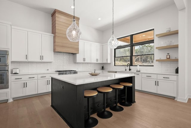 kitchen featuring light wood finished floors, white cabinets, a center island, and light countertops