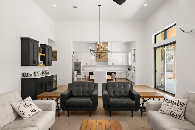 living room with light wood finished floors, recessed lighting, a high ceiling, and an inviting chandelier