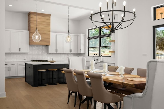 dining area featuring recessed lighting, a chandelier, a high ceiling, and light wood-style flooring