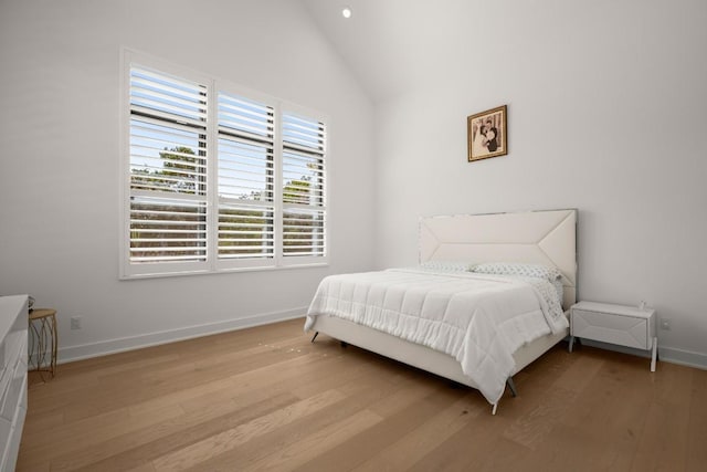 bedroom with baseboards, lofted ceiling, and wood finished floors