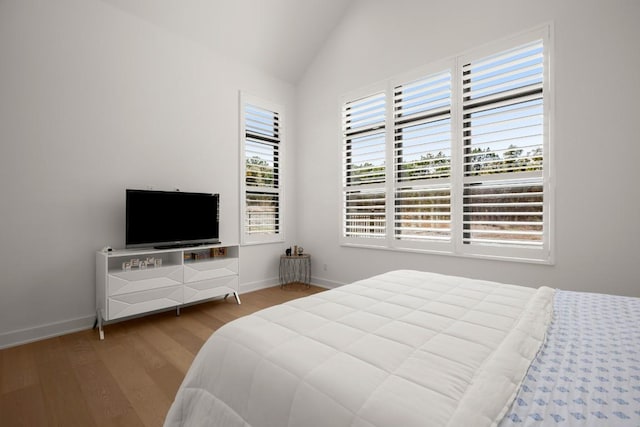 bedroom with lofted ceiling, wood finished floors, and baseboards